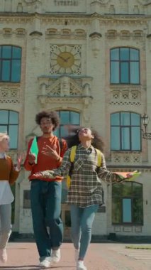 Mutlu çok ırklı üç öğrenci kutluyor hava yürüyüşü yapan üniversite Kafkas kız kadın Afrikalı erkek erkek sınıf arkadaşları üniversiteden mezun olup sınavlara giriyor.