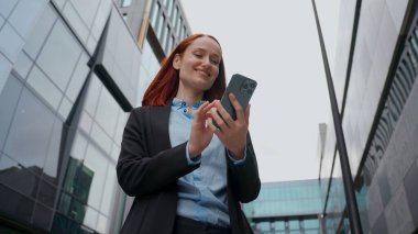 Kafkasyalı iş kadını işveren gülümsemesi ile cep telefonu sohbetleri ile şehir merkezindeki kadın kaygısız, pozitif yönetici iş kadını sosyal medya mesajlaşması uygulaması akıllı telefon
