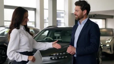 Beyaz adam müşteri alıcısı otomobil galerisinde kadın satış elemanı ile tokalaşıyor tüccar el sıkışan işadamıyla konuşuyor ve yeni bir araba sözleşmesi alıyor kadın temsilcisi oto kiralama servisi alım satımı yapıyor.