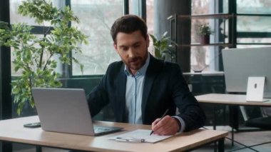 Ofiste dizüstü bilgisayarda çalışan başarılı Kafkas işadamı erkek yönetici girişimci lideri bilgi notları yazıyor iş adamı muhasebe işleri işvereni içeride bilgisayar işyeri daktilo ediyor.