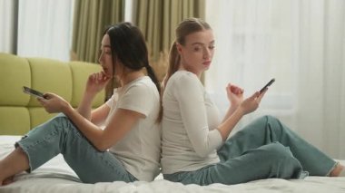 İki farklı kadın yataklarına uzanıp sohbet ediyor. Çatışma sonrası cep telefonları sohbet ediyorlar. Kafkas Asyalı Koreli Çinli Çinli kadın evde internet bağımlısı akıllı telefonlara bakıyorlar.