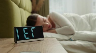 Kafkasyalı bir kadın sabah uyandığında çalar saatle uyanıyor kızgın yorgun kız yeni bir gün evde uyanıyor yatak odasında uykusuzluk çekiyor yüksek sesli bir ses çınlayan kadın cihaz sağlığını bozuyor.