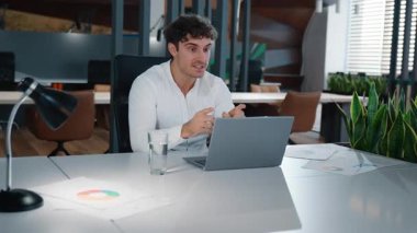 Neşeli gülümseyen mutlu beyaz iş adamı konuşuyor. Bilgisayarı kapatıyorum. Erkek konferansında başarılı bir iş adamı olarak düşünüyorum.