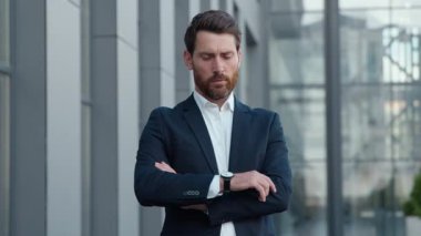 Profesyonel Kafkasyalı iş adamı, geç saatlerde kameraya bakan olgun, orta yaşlı bir iş adamının şehirdeki girişimciyi işaret ederek saati kontrol edişini gösteren bir toplantı için kol saatine bakıyor. Yüksek