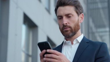 Şehirdeki Kafkasyalı yetişkin işleri üzgün cep telefonlu olgun iş adamlarının akıllı telefondan kötü haberler okuması olumsuz mesajlar tatmin olmamış erkek memnun değil ve internet başvurusu reddediliyor.