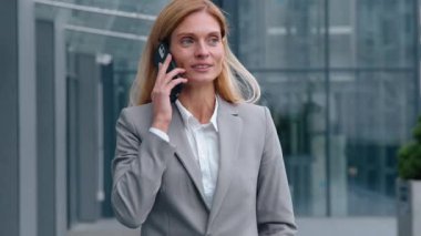 Gülümseyen Kafkasyalı yetişkin iş kadını şehirde yürüyor iş görüşmesi yapıyor orta yaşlı kadın şirket liderini tartışıyor sohbet etmeye gidiyor iş konuşmaya gidiyor şehir merkezindeki sohbete gidiyor