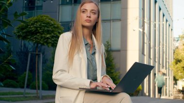 Düşünceli Kafkasyalı iş kadını dışarıda dizüstü bilgisayarda yazı yazıyor. Düşünceli kadın iş kadını gazeteci. Uzaktan kumandalı online yazım planı üzerinde çalışıyor.