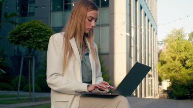 Şehir merkezinde dizüstü bilgisayarı daktilo eden düşünceli, düşünceli beyaz iş kadını serbest girişimci, yazar, yazar, uzak bir internet sitesi.