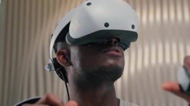 3D dünya oyunları oynayan Afrikalı Amerikalı erkek kontrolör VR başlık kullanıyor sanal artırılmış gerçeklik gözlükleri yüksek teknolojili internet teknolojisi fütürizm siber oyun arayüzü yenilik metaevren oynuyor