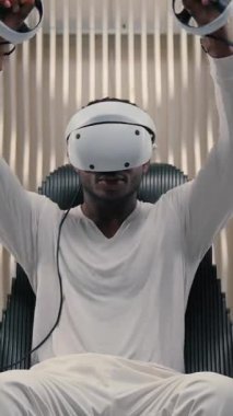 Sanal gerçeklikte Afrikalı Amerikalı bir adam gelecekteki uzayda el kaldırma, kol kaldırma, kontrolörleri tutma, erkek adam VR oyunu oynuyor siber yenilik yenilikçiliği teknolojisi miğferini kullanarak.