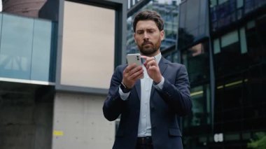 Şehirdeki düşünceli iş adamı Kafkasyalı. Cep telefonu kullanıyor. İnternette arama yapıyor. Cep telefonunu arıyor.