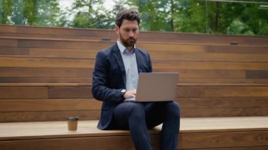 Kafkasyalı iş adamı laptopunu daktilo ediyor dışarıda çalışıyor kahve fincanı içiyor erkek girişimci iş adamı serbest çalışan müşterisi dışarıda bilgisayardan internet araştırması yapıyor.