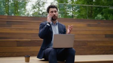 Kafkasyalı çoklu görev sahibi iş adamı dışarıda cep telefonu iş adamı, iş adamı, iş adamı, şehirde çalışan, gülümseyen, akıllı telefonlu, internetten internet bağlantısı yazan adam.