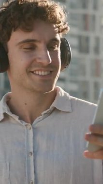 Cep telefonu ile tasasız Kafkasyalı iş adamı. Kulaklıkla müzik dinliyor. İş adamı, erkek, yönetici, dans ediyor.