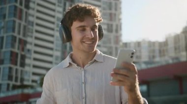 Cep telefonu ile tasasız Kafkasyalı iş adamı. Kulaklıkla müzik dinliyor. İş adamı, erkek, yönetici, dans ediyor.