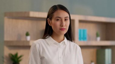 Kendine güvenen Asyalı Koreli iş kadını liderinin portresi silah ofisi başarılı kadın CEO 'su Çinli iş kadını kadın yönetmen kapalı mekan jestine bakıyor.