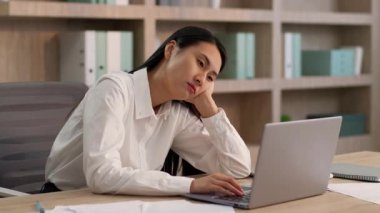 Sıkıcı, tembel, Asyalı, Çinli bir iş kadını ofiste dizüstü bilgisayar yazarken yorgun düşmüş Koreli kadın iş kadını Japon iş kadını bilgisayar çalışanı sıkıcı iş motivasyonsuz iş.