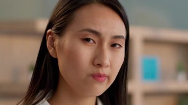 Kapatın üzgün Asyalı iş kadını mutsuz ofis çalışanı kameraya bakıyor dalgın Çinli kadın Japon girişimci düşünceli iş kadını kapalı alanda ifade portresi