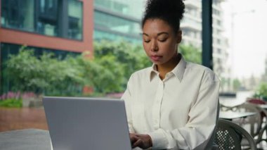 Şehirde dizüstü bilgisayar yazan konsantre Afro-Amerikan iş kadını şehir merkezindeki kadın işverenin bilgisayarında çalışıyor internet kullanarak ciddi girişimci bayanları çalıştırıyor.