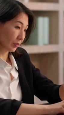 Dizüstü bilgisayarda yazı yazan Asyalı bir iş kadını Çinli bir iş kadınını rahatsız ediyor. Bilgisayarda çalışıyor. Görüşü bulanık Koreli bir Japon bayanın ofisinde baş ağrısı var.