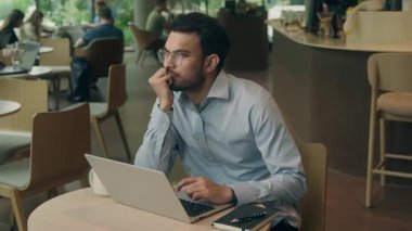 Etnik Hintli iş adamı üzgün düşünceli dizüstü bilgisayarla fikir üretmek iyi bir karar. Bilgisayarlı iş adamı erkek problem çözmede çalışıyor. İnternet işi kafede tereddüt ediyor.