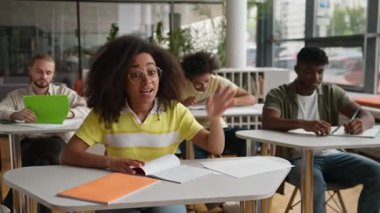 Afrika kökenli Amerikalı öğrenci inek öğrenci, kolunu kaldıran zeki kadın, oditoryumdaki öğretmenle konuşuyor. Dört etnik çeşitlilik gösteren öğrenci, ders eğitiminde öğrenim görüyor.