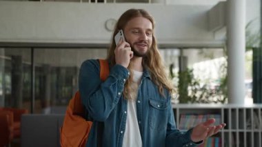 Neşeli Kafkasyalı öğrenci cep telefonuyla konuşuyor. Akıllı telefonla konuşuyor. Haber sunan adam gülüyor.