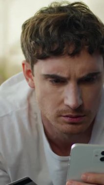 Mutsuz Kafkasyalı adam elinde akıllı telefon kredi kartı ödemesi hatası endişeli erkek adam sorunu online işlem başarısızlığı para kaybı finansal borç batması stres teknolojisi