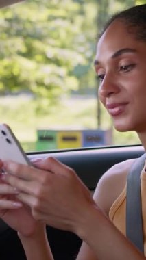 Şaşırtıcı mutlu Afro-Amerikan kadın cep telefonu kullanıyor içeride gülümsüyor neşeli kadın şoför iş kadını iyi haberlerin tadını çıkarıyor yeni otomobil taşımacılığı zaferine gülüyor