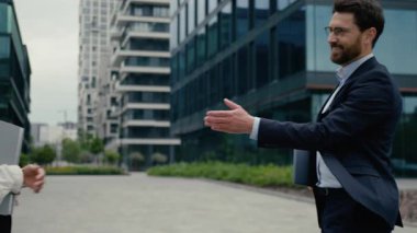 Şehirdeki çok ırklı iş ortakları tokalaşması. Beyaz erkek, Afro-Amerikalı iş kadınlarını selamlıyor. İş ortakları iş arkadaşlarını tartışıyor.