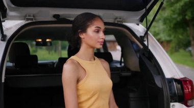 Mutlu gülümseyen Afro-Amerikan kadın kameraya bakıyor. Yeni araba bagajı açık hava gezisinde bayan sürücü. Gezgin kız iş kadını.