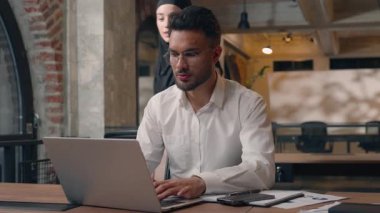 Görevdeki Müslüman iş adamları iki ortak dizüstü bilgisayar arayan iki erkek ve kadın Arap erkek işadamı stajyeri, tesettürdeki patron kadın iş kadınından iş danışmanı hakkında bilgi istiyor.