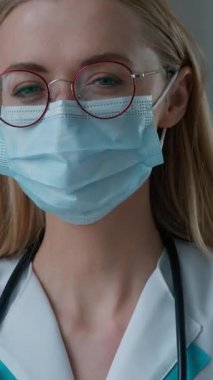 Üniformalı beyaz doktor kadın doktor maskesini gösteren portre, tamam işareti onaylıyor. Kamera içine bakıyor. Hemşire kadın terapist.