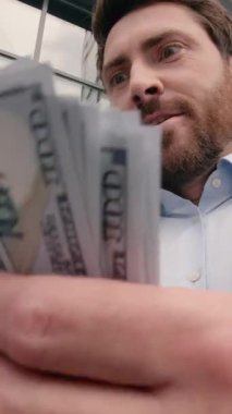 Zengin, mutlu, beyaz, orta yaşlı iş adamı para sayıyor. Şehirde ofis yakınında gülümsüyor. Maaş başarısını kutlayan heyecanlı erkek işadamı.