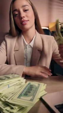 Neşeli Kafkasyalı iş kadını elinde dolarlarla gezen zengin bir kadının hayranı masa başı kadın iş kadınına gülümsüyor mutlu yığınlar halinde banknotlar maaş gelir bankası para biriminin keyfini çıkarıyor.