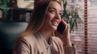 Neşeli Kafkasyalı iş kadını cep telefonuyla konuşuyor. Ofiste gülümsüyor. Kaygısız kız, iş kadını, yönetici işveren, akıllı telefondan konuşuyor.