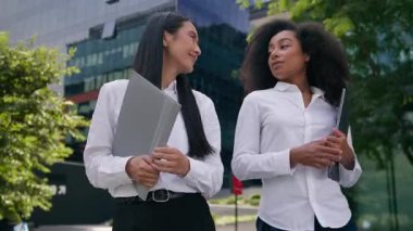 Çoklu etnik çeşitliliğe sahip Afrikalı iş kadınlarının müzakere şehrinde neşeli iş kadınları hakkında konuşması klasörde yürüyen iş arkadaşları iş arkadaşlarıyla şehir içi toplantıları hakkında konuşması