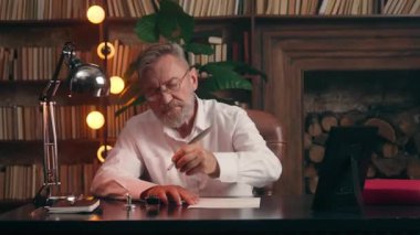 Eski Kafkasyalı emekli işadamı. Tüy tüyü ile mürekkep batırma mürekkebi ile mürekkep mürekkebi mürekkebi ile mürekkep kâğıdı dökümanı imzalıyor. Yaşlı işadamı, yazar, ev ofis masasında yazıyor.