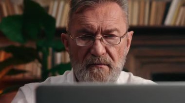 Kendine güvenen Kafkas kıdemli yetişkin iş adamı online emeklilik işadamı bilgisayarda çalışıyor çevrimiçi siber uzay emeklisi patronuyla çalışıyor ofiste sohbet ediyor.