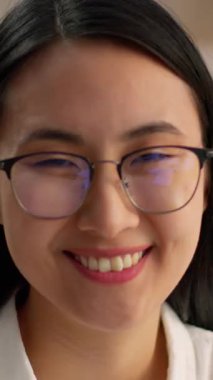 Yakın plan mutlu Asyalı Asyalı iş kadını kadın yönetici gülümseyen Çinli Koreli iş kadını kadın işçi sekreter işveren gözlüklü ofis kamerasına bakıyor.