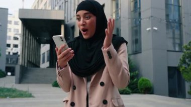 Mutlu Müslüman iş kadını siyah tesettürlü cep telefonuyla kazanan İslami iş kadını şirketinde, bağıran bir kıza ulaşmayı başaran başarılı bir iş kadını.