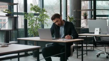 Ofiste laptopla yazı yazan Kafkasyalı iş adamı cep telefonuyla konuşuyor profesyonel erkek müdür tartışıyor cep telefonundan memnun olmayan işadamının notlar yazdığını savunuyor.