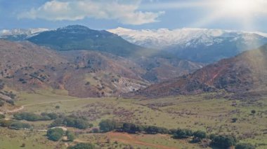İspanya 'daki Sierra Nevada dağlarının güneşli panoramik manzarası. Karla kaplı tepeler yuvarlanan yeşil tepeler parlak gökyüzü manzaralı kayalar Endülüs manzarası doğal güzelliği yansıtan barışçıl atmosfer.