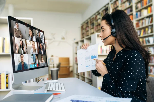 Çevrimiçi video konferansı. Çok ırklı başarılı iş arkadaşlarıyla bilgisayar monitörü görüntüsü ve iş kadını onlara bir grafik gösteriyor