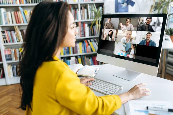 Çevrimiçi öğrenme. Online ders sırasında bir kız öğrenci diğer öğrencilerin ve bir öğretmenin ders verdiği monitöre bakar.