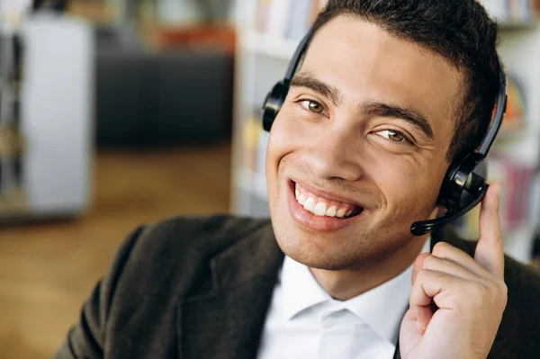 Close up portrait of a friendly smiling hispanic or caucasian man wearing headset for working online, call center operator, consulting of client, or a student which learning language online