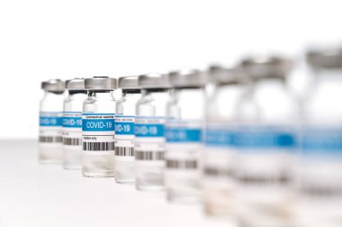 Beyaz zemin üzerinde COVID-19 Corona virüsü aşısı olan ampuller. Coronavirus aşısı imalatı, dünya çapında aşı ve sağlık konsepti