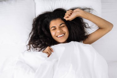 Tatmin olmuş genç bir Afrikalı Amerikalı kadın sabah uyandığında kendini dinç ve neşeli hissediyordu. Güzel bir kadın yatakta dinleniyor, gözleri kapalı gülümsüyor evde dinleniyor, sağlıklı bir uyku çekiyor.