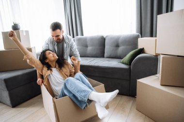 Taşındığı gün çok ırklı mutlu bir çift. Karton kutularla eğlenen, güzel karısı olan neşeli bir koca, eşyaları yerleştirirken. Tatmin olmuş kadın ve erkek gülümsüyor.