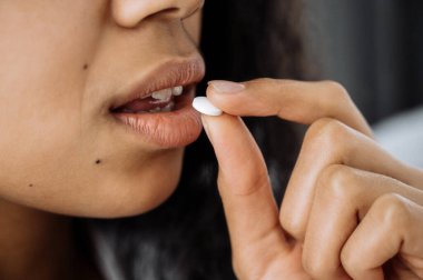 Kadın hap alıyor. Kadın elindeki hapın yakın plan fotoğrafı. Afrikalı Amerikalı kadın, kötü hissettiğin için hap al. Sağlıksız kadın stres, hastalık ya da griptir. Hastalık konsepti